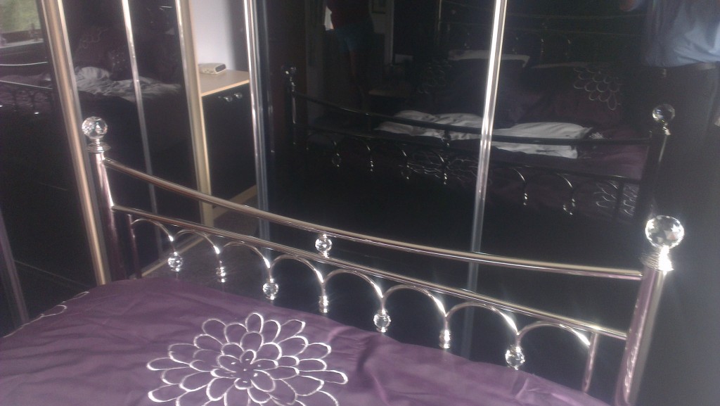 View looking from bed of luxury Black glass doors with polished chrome framework.